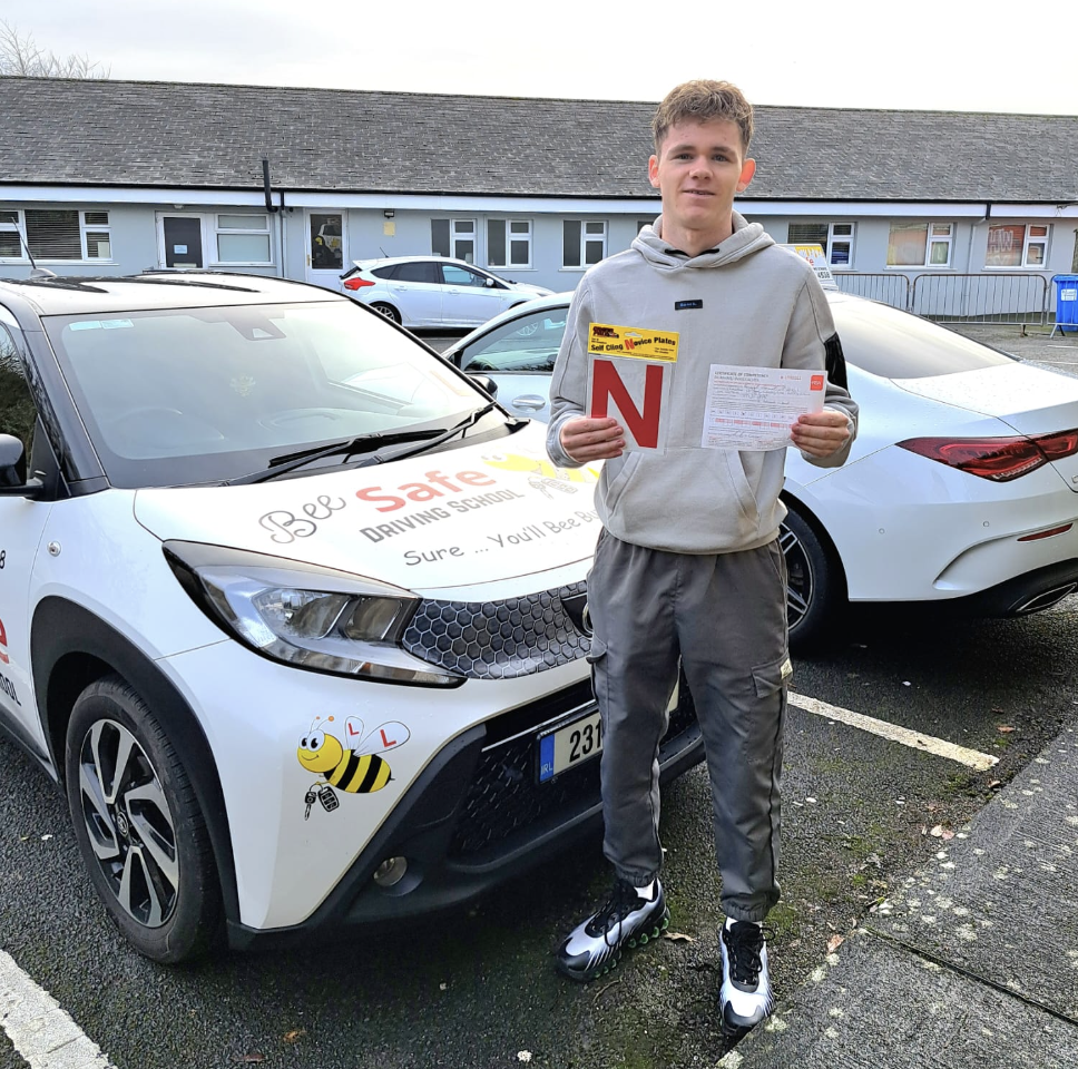 Bee Safe Driving School student holding novice plates and paperwork beside the tuition car
