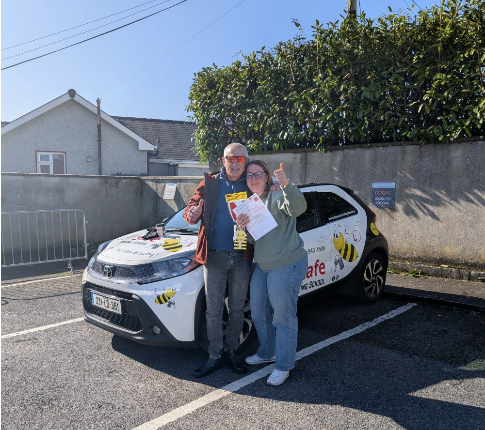 Bee Safe Driving School student celebrating in front of the tuition car after passing